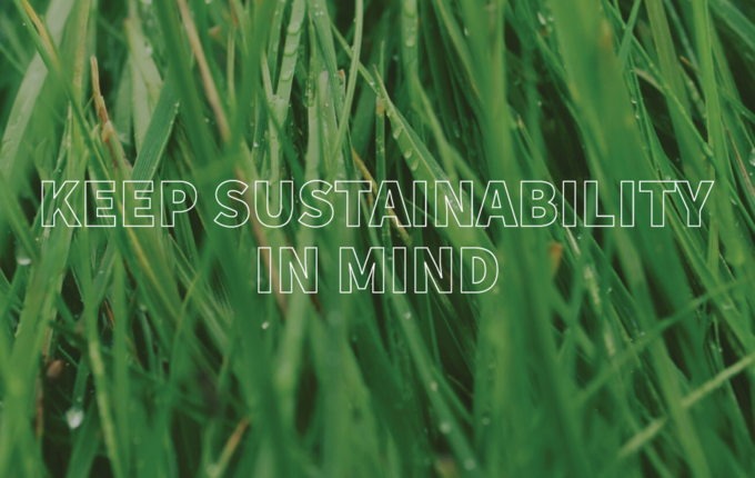 Wet blades of grass with text that reads: keep sustainability in mind like Gildan.